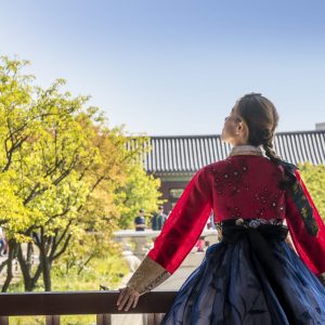A woman in traditional Korean clothing  looking up at the sky
